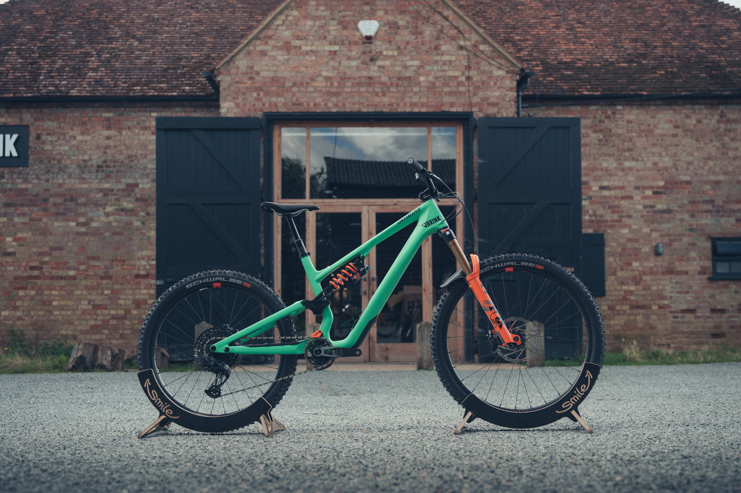 Green mountain bike on a stand in front of a brick building