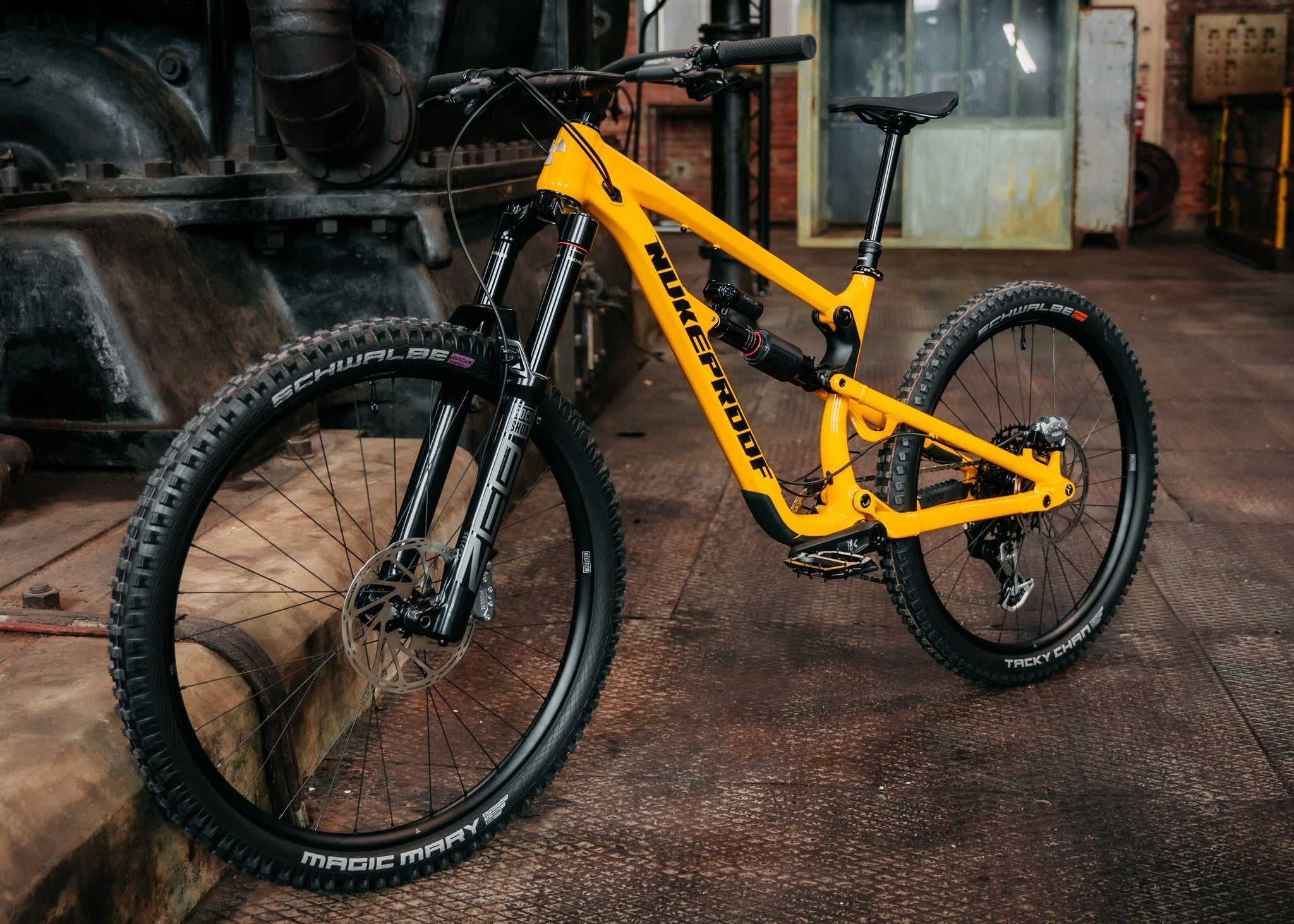 Yellow mountain bike in an industrial setting with large pipes and brick walls.