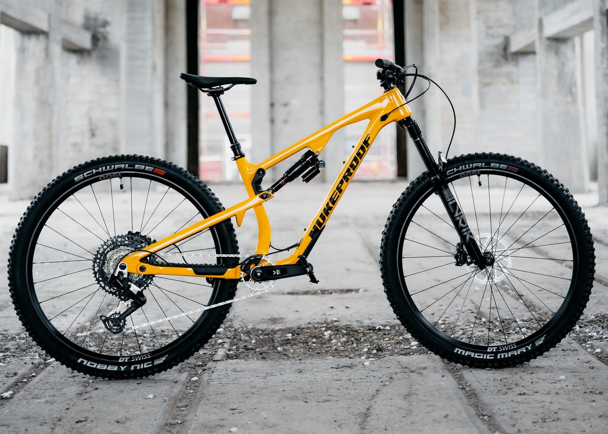 Yellow mountain bike on a concrete surface with a concrete building in the background
