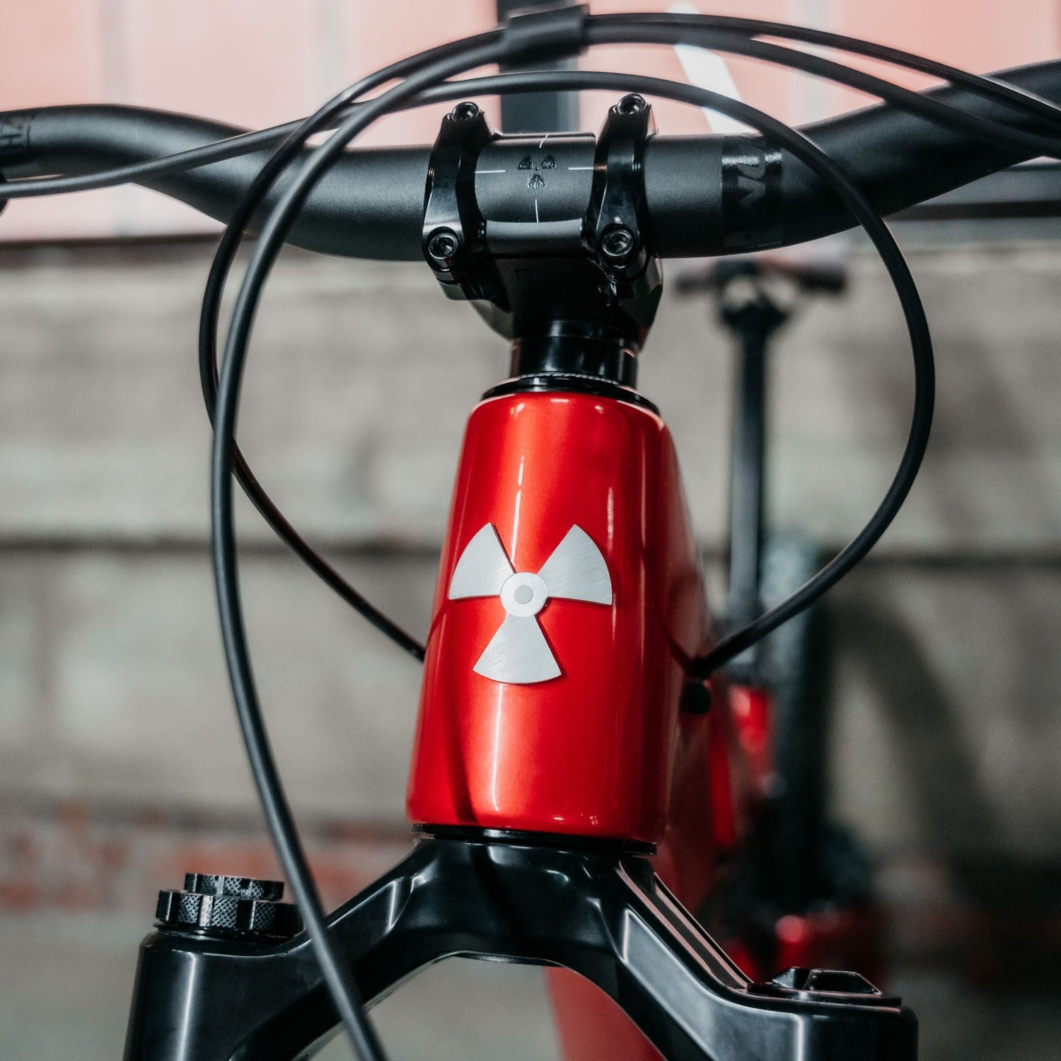 Close-up of a bicycle handlebar with a red and black design, featuring a white symbol on a blurred background.