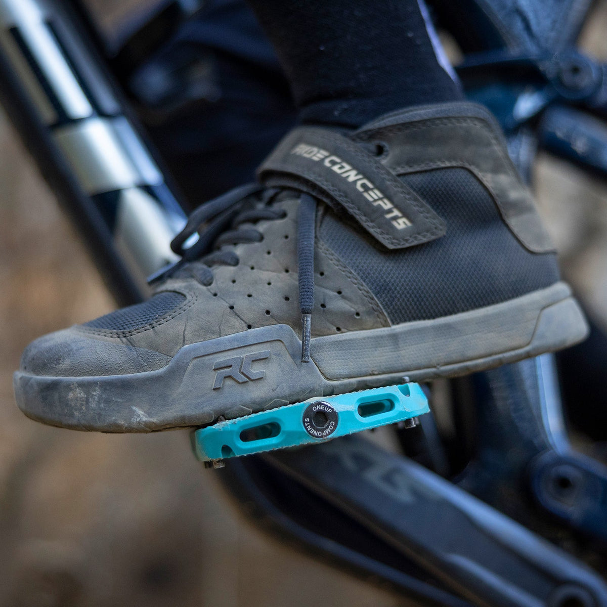Shoe resting on a turquoise OneUp Small Composite Pedal