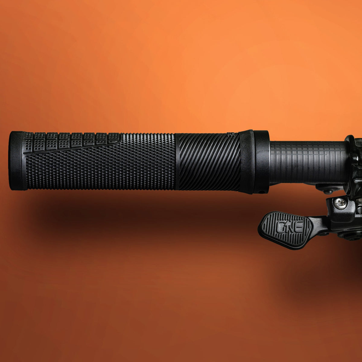 Slim black OneUp Thin Grip mounted against an orange backdrop