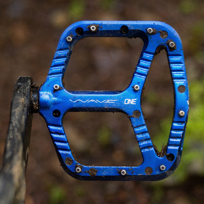 Dark blue OneUp Wave pedal installed on a muddy bike