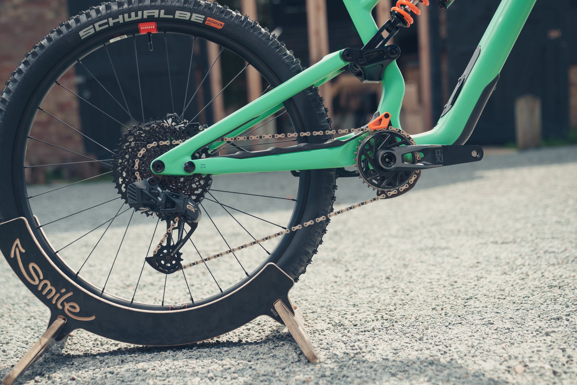 Close-up of a green bicycle with a smiley face design on the tire, parked on a concrete surface.
