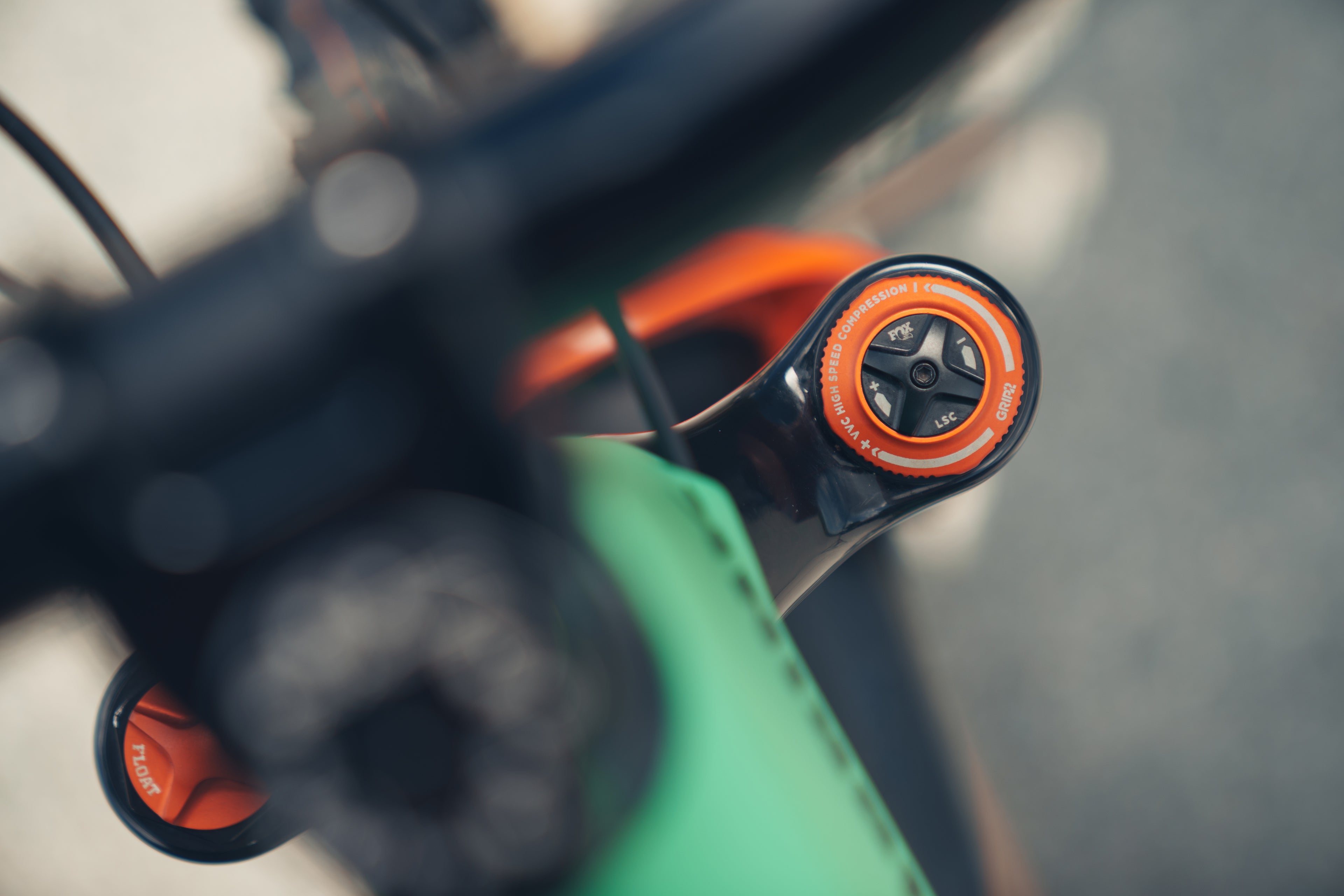 Close-up of a bicycle handlebar with orange grips and a blurred background
