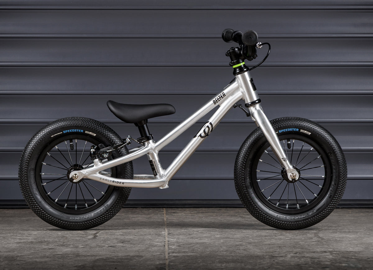 Early Rider Belter 12 Balance Bike in Brushed Aluminium - brushed balance bike profile against shutters with low frame