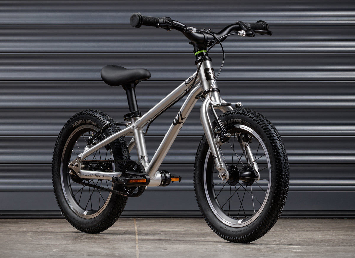 Early Rider Belter 14 in Brushed Aluminium - three-quarter whole bike against grey shutters