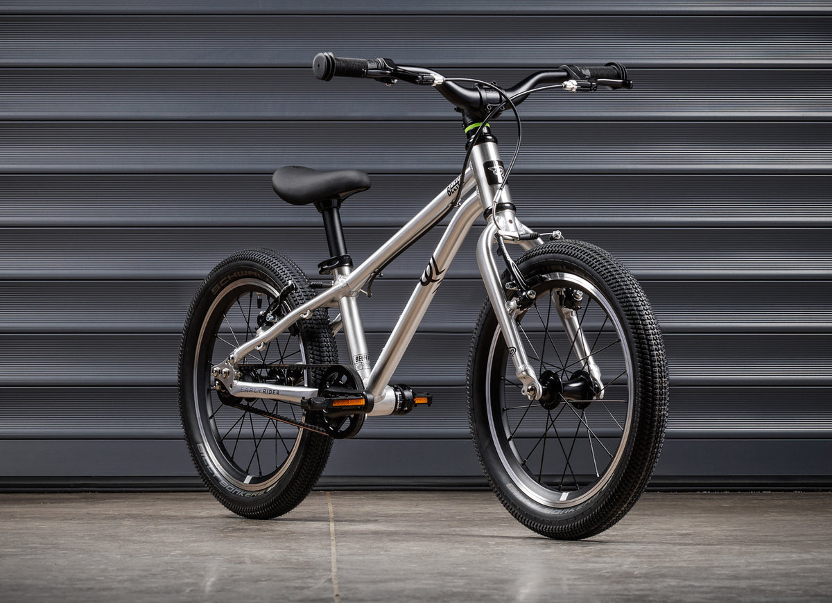 Early Rider Belter 16 in Brushed Aluminium - standard single-speed whole bike against shutters