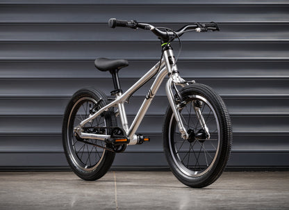 Early Rider Belter 16 in Brushed Aluminium - standard single-speed whole bike against shutters