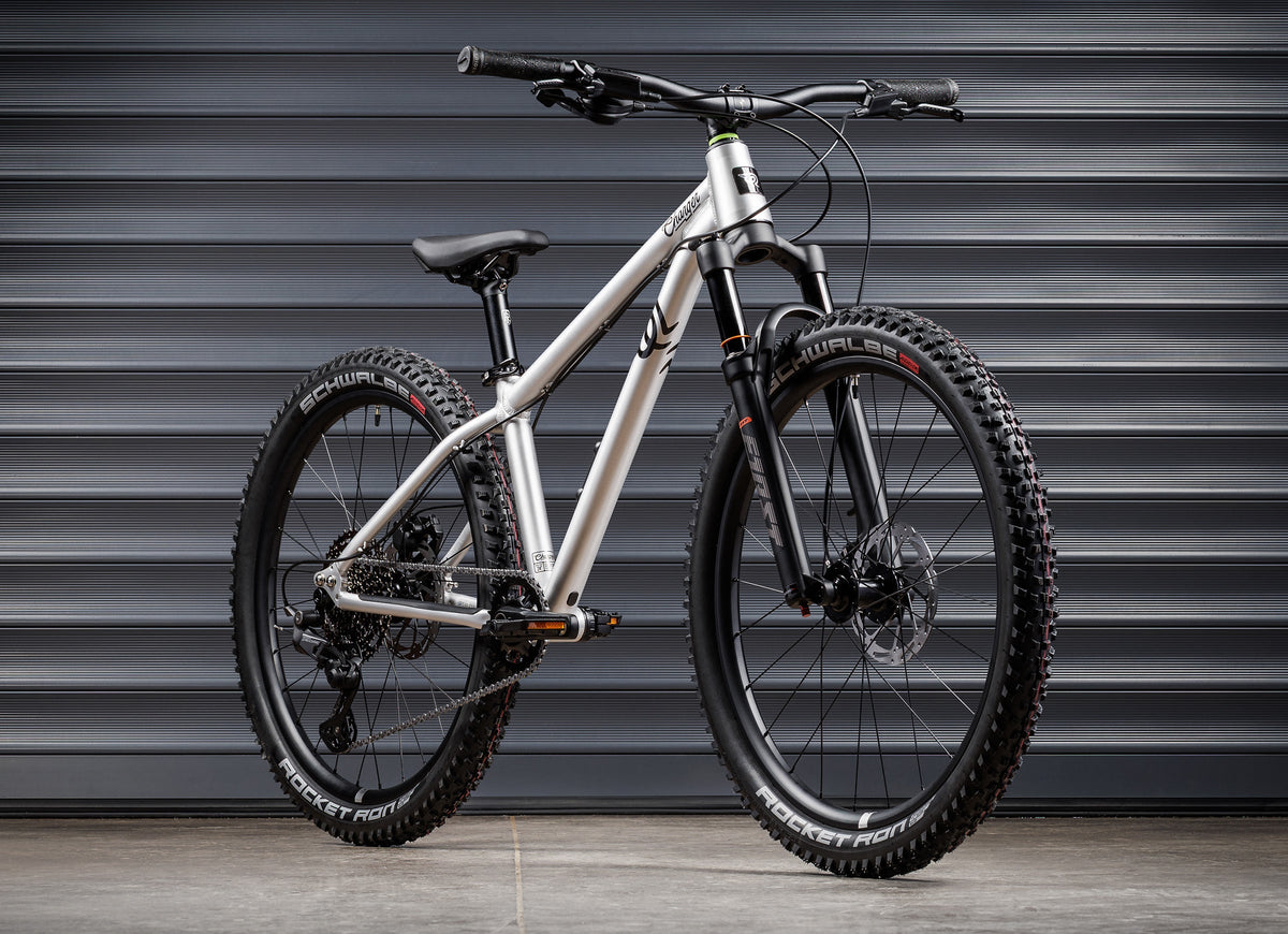 Early Rider Charger 24 in Brushed Aluminium - whole bike against shutters