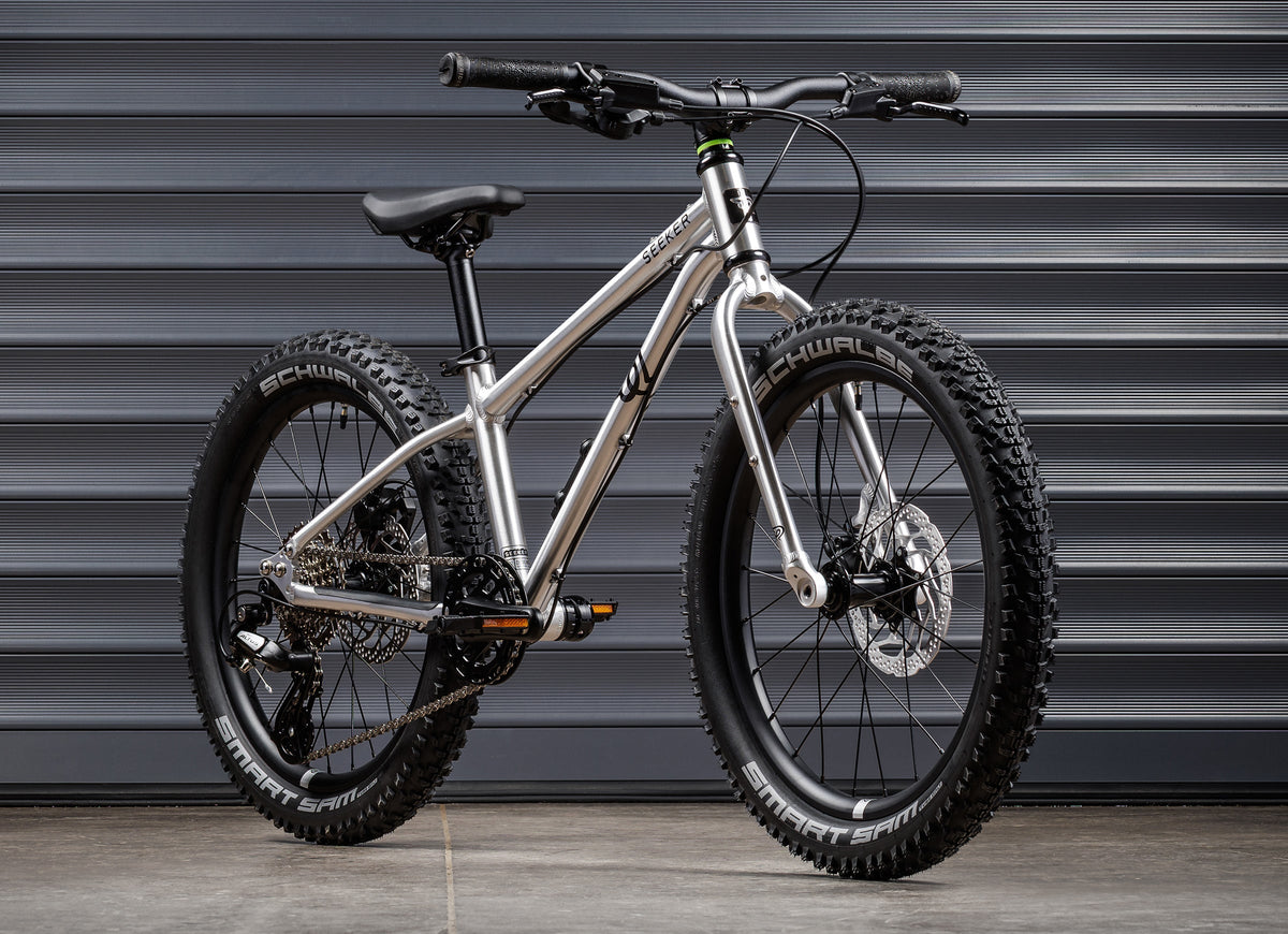 Early Rider Seeker 20 in Brushed Aluminium - whole bike against shutters