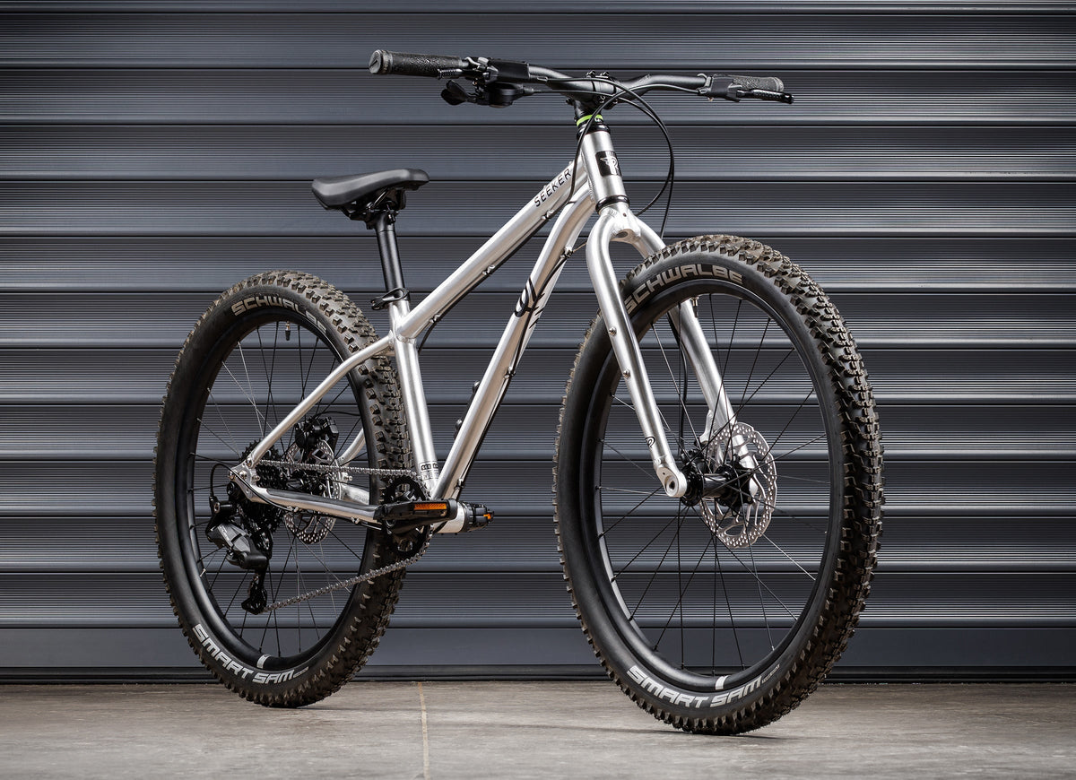 Early Rider Seeker 24 in Brushed Aluminium - whole bike against shutters