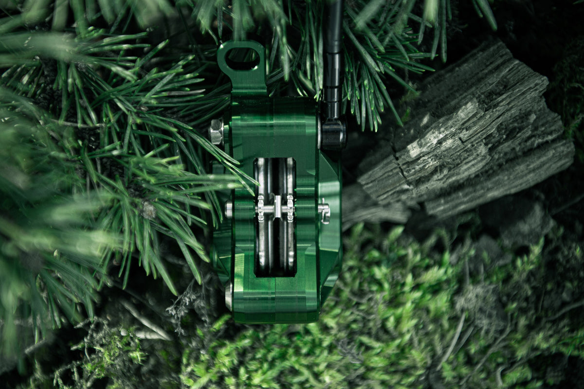 Top view of a green Trickstuff Direttissima caliper showing its brake pads and hose connection.