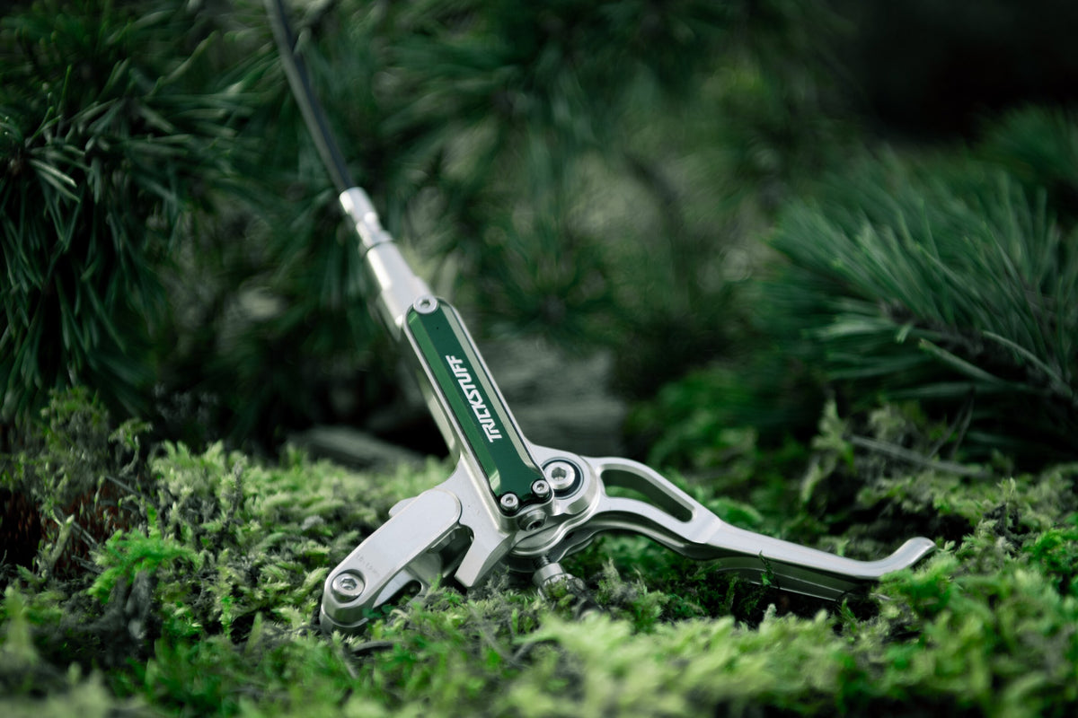 Silver Trickstuff Direttissima lever and pump with a green reservoir cap resting on moss.