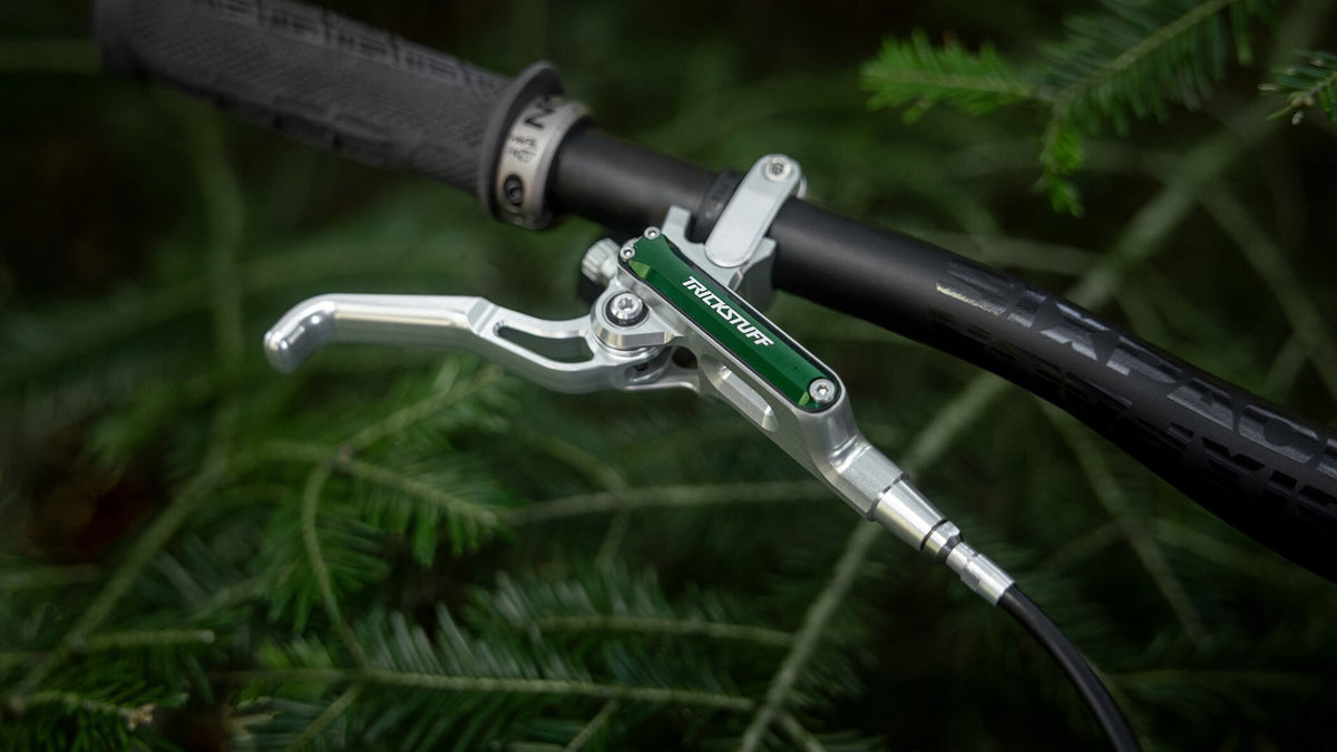 Silver Trickstuff Direttissima brake lever with a green reservoir cap mounted on a black handlebar.