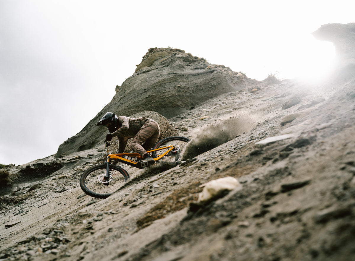 Mountain biker carving a loose rocky slope in Trickstuff Maxima campaign imagery.