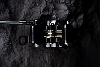 Top view of a black Trickstuff C42 caliper with the pads and retaining bolt visible.